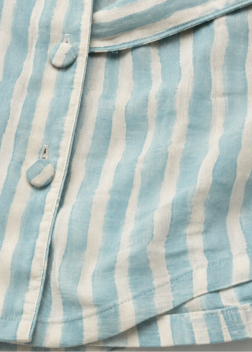 Close-up of a blue and white striped shirt with buttons on a light background