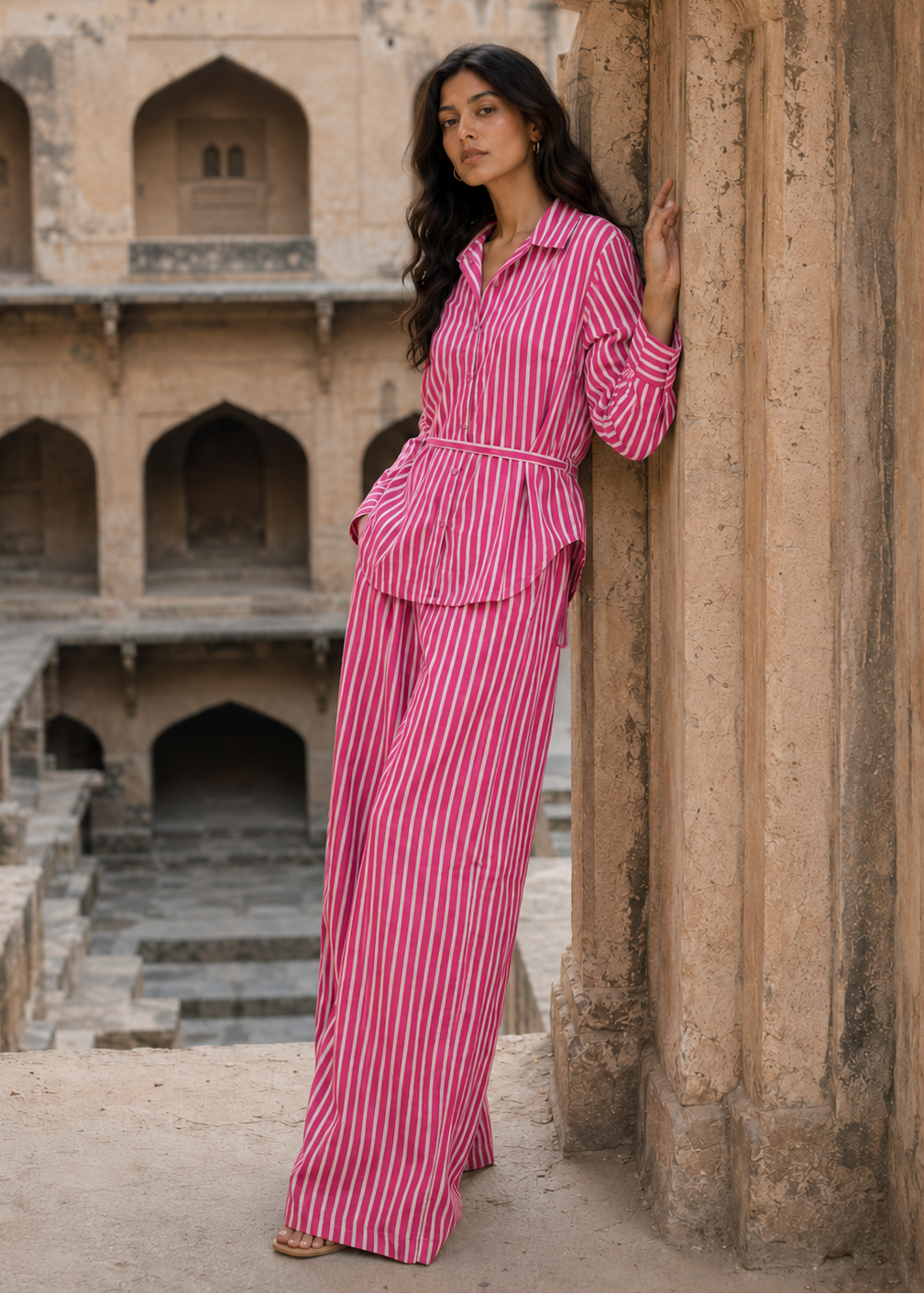 Woman in a pink striped outfit standing in an ancient architectural setting