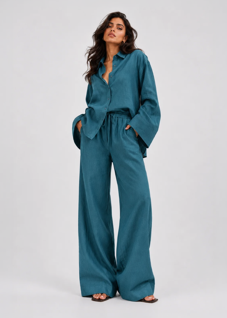 Woman wearing a teal outfit with wide-leg pants on a white background