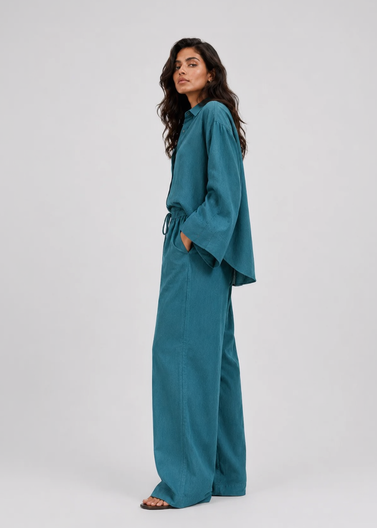 Woman wearing a teal outfit on a white background