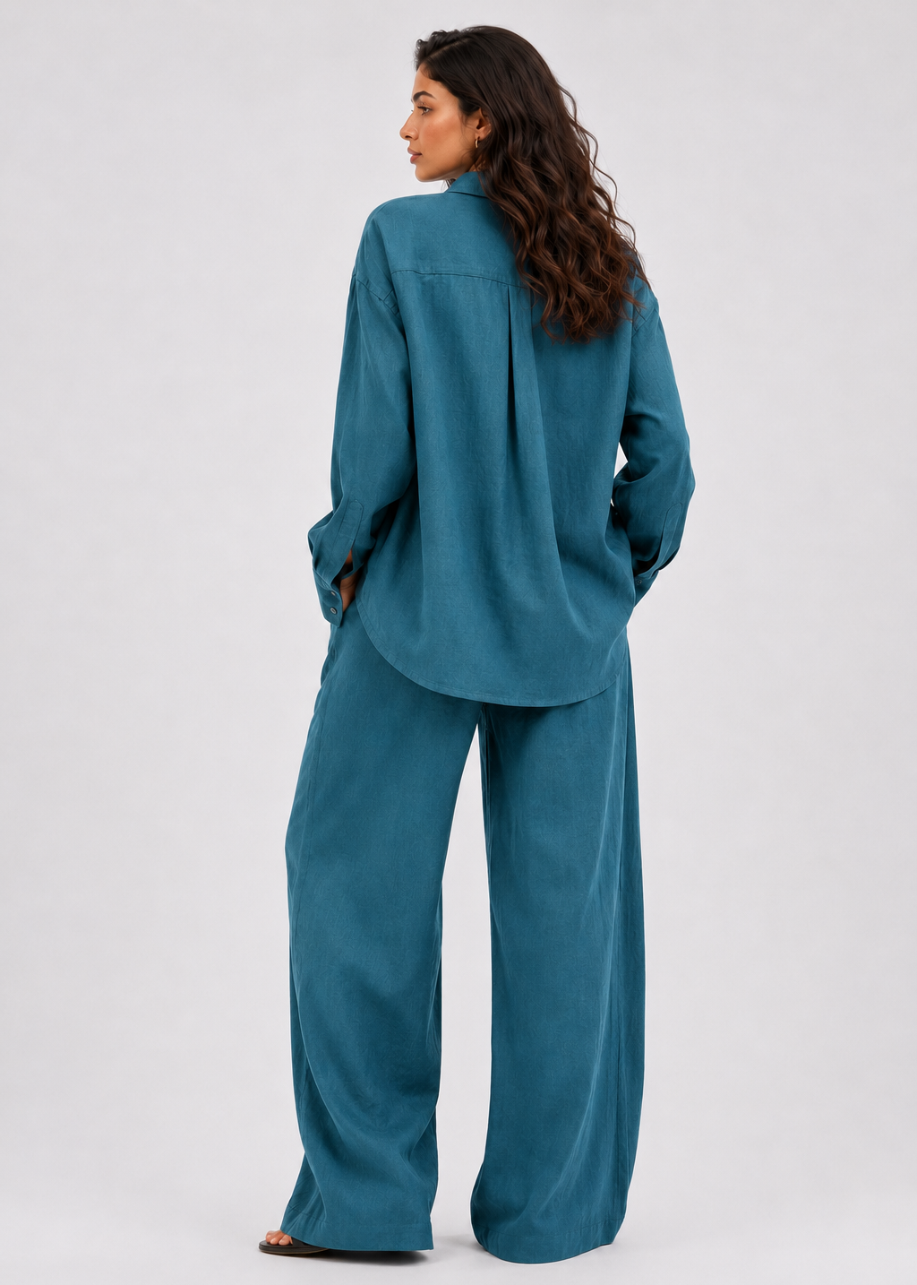 Woman wearing a teal suit standing against a white background
